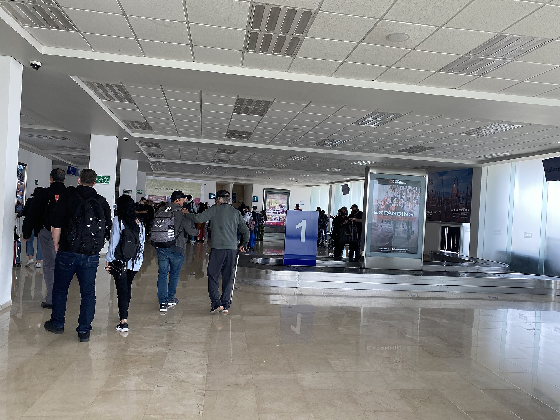 Passengers walking toward the baggage claim belt in the arrivals hall of Oaxaca International Airport