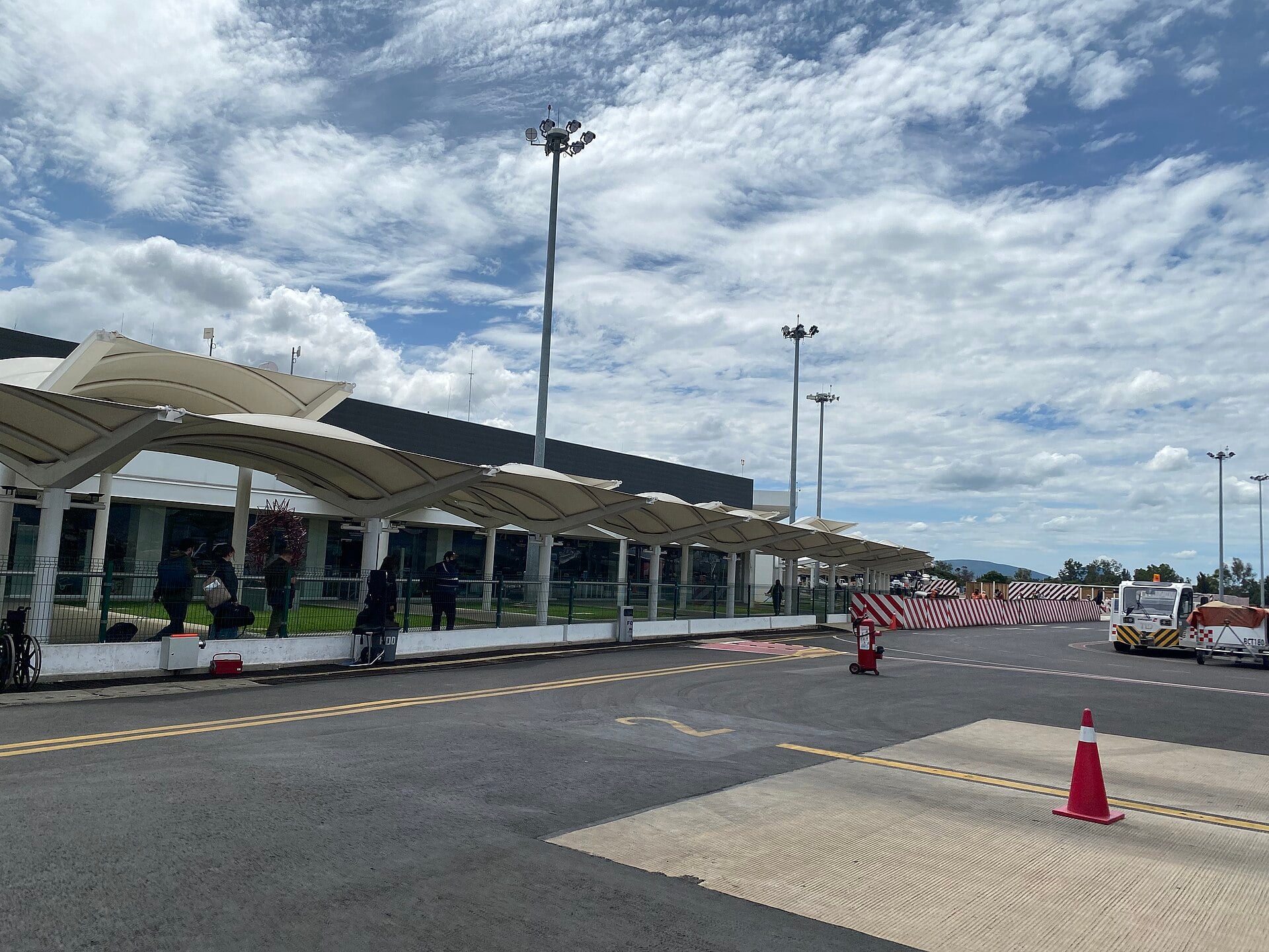 Exterior of Oaxaca International Airport terminal with canopy and apron on a cloudy day