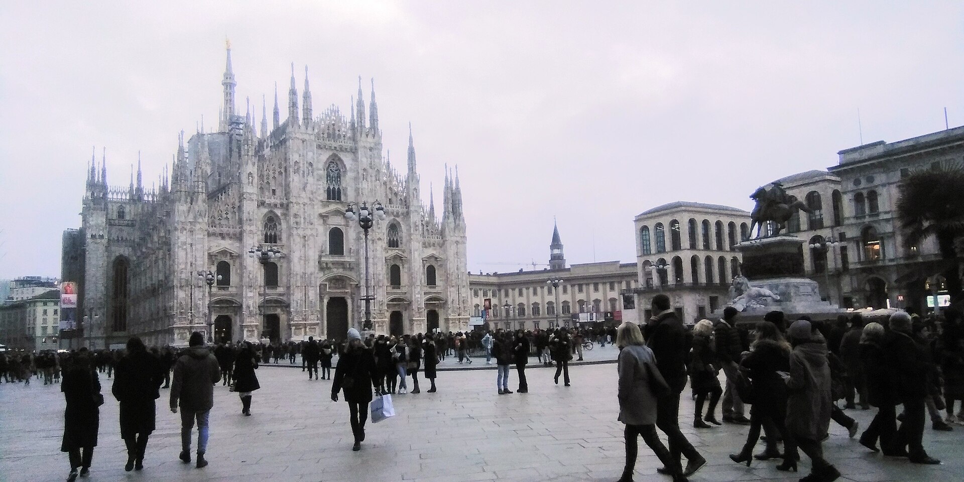 Pedestrians crossing Piazza Duomo in Milan with the cathedral in the background.
