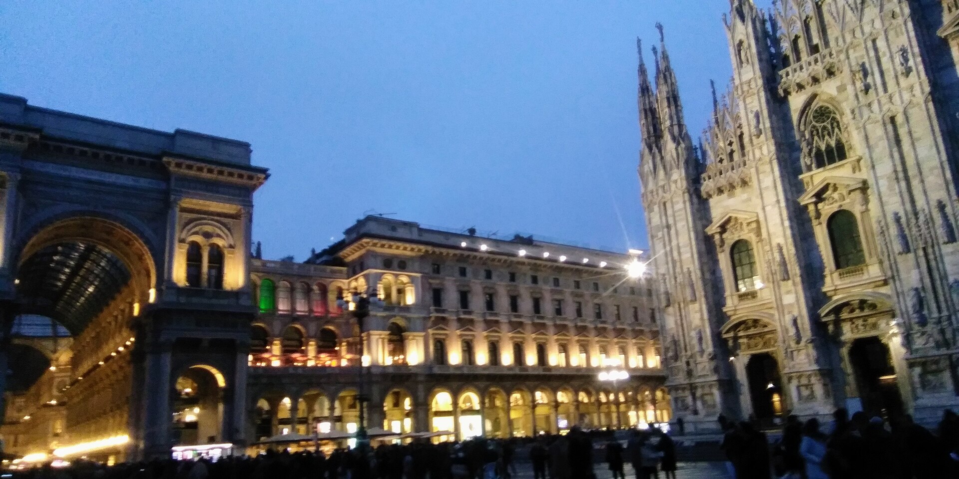 Piazza Duomo in Milan at twilight with the cathedral on the right and the Galleria on the left.