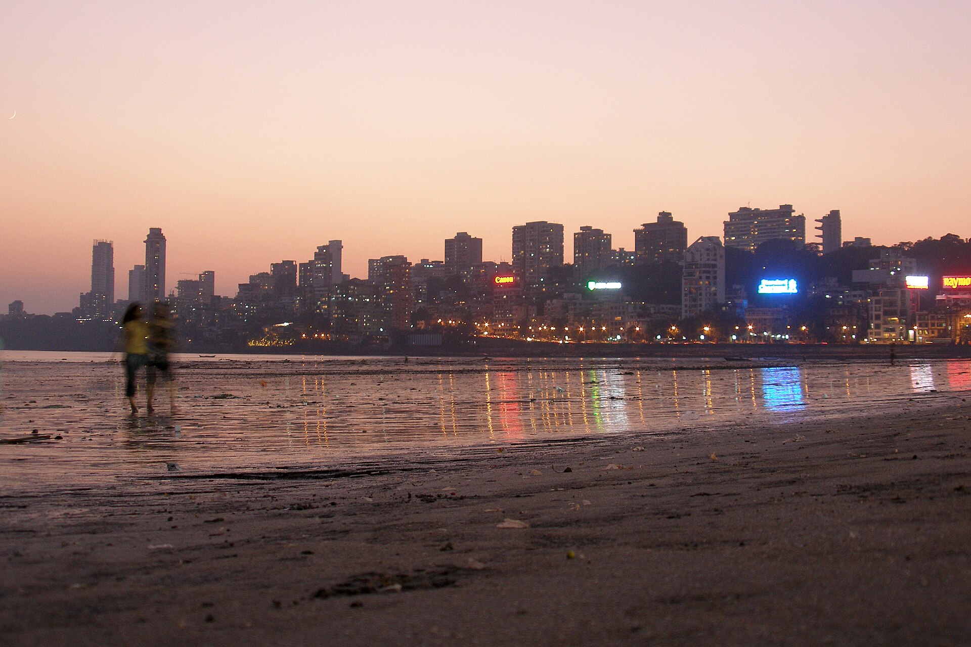 Mumbai skyline at dusk seen from Chowpatty beach, with lit towers along the shore