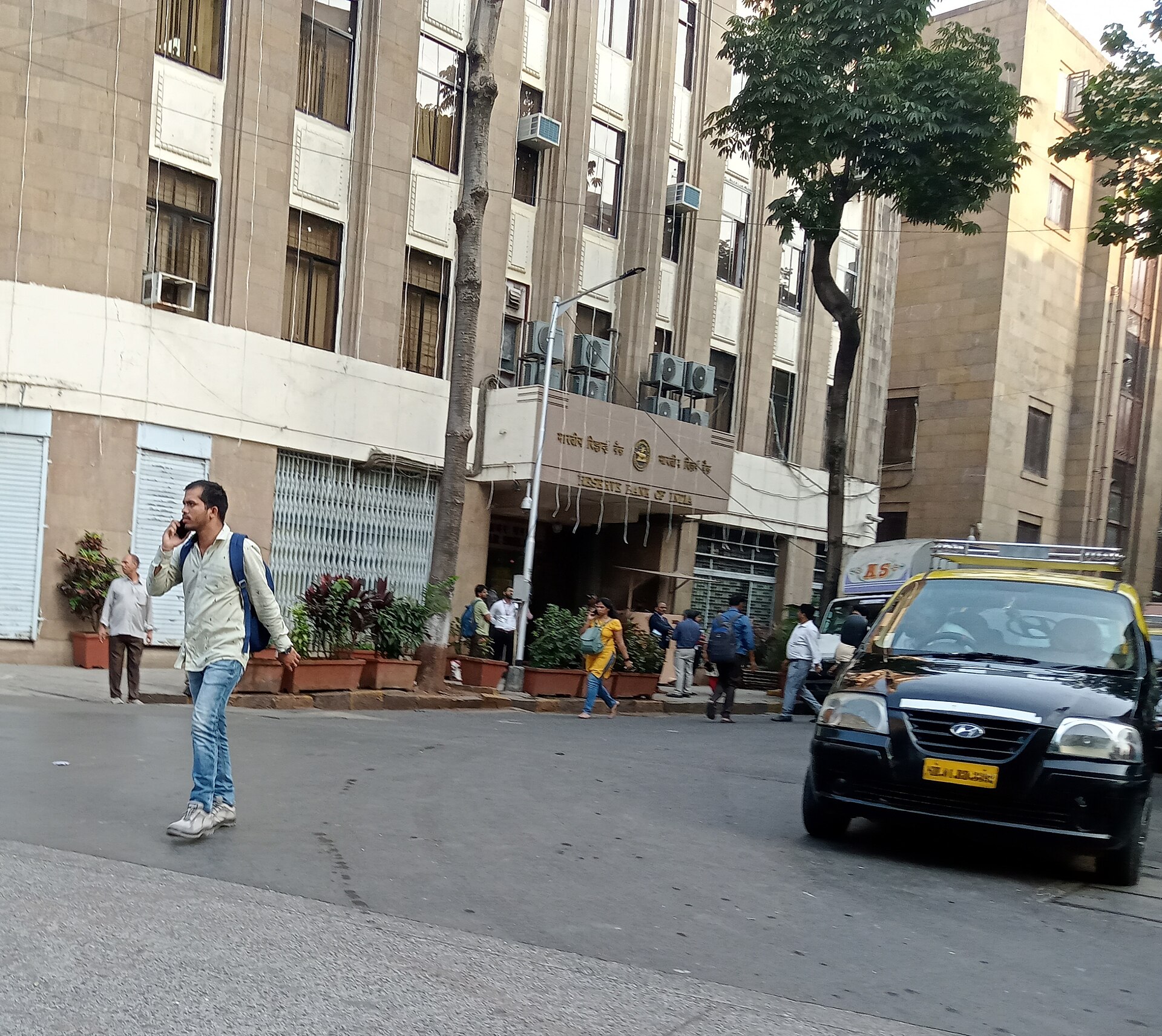 Pedestrians and a taxi on a street outside Reserve Bank of India offices in Mumbai.