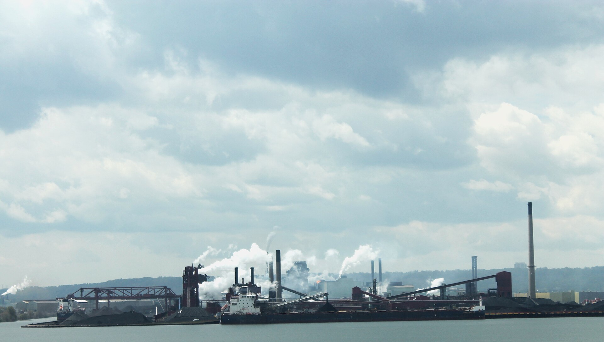 Industrial steel mill with smoking chimneys and a ship at the dock in Hamilton, Ontario.