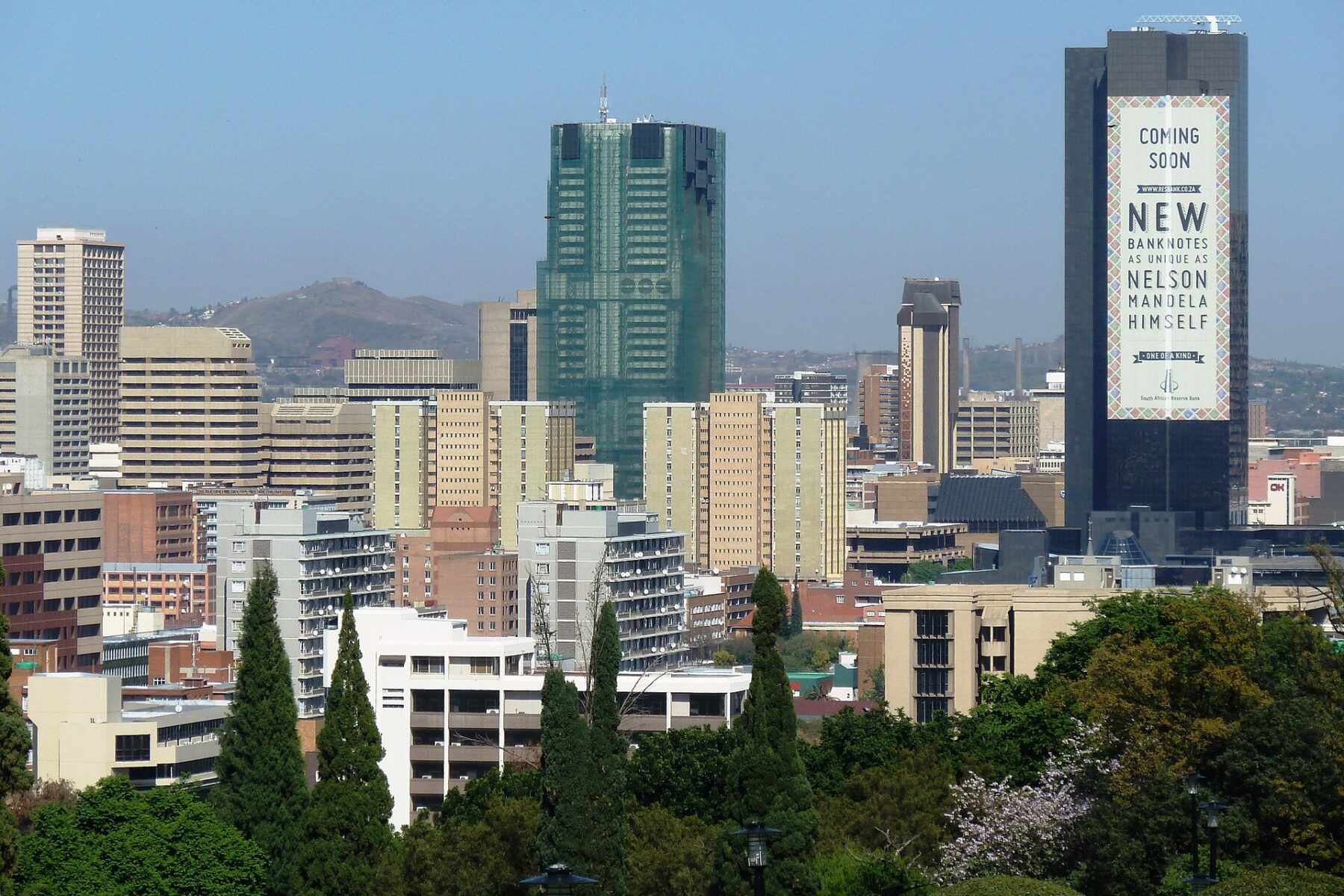 Pretoria city centre skyline with the dark South African Reserve Bank tower on the right carrying a large banknote banner
