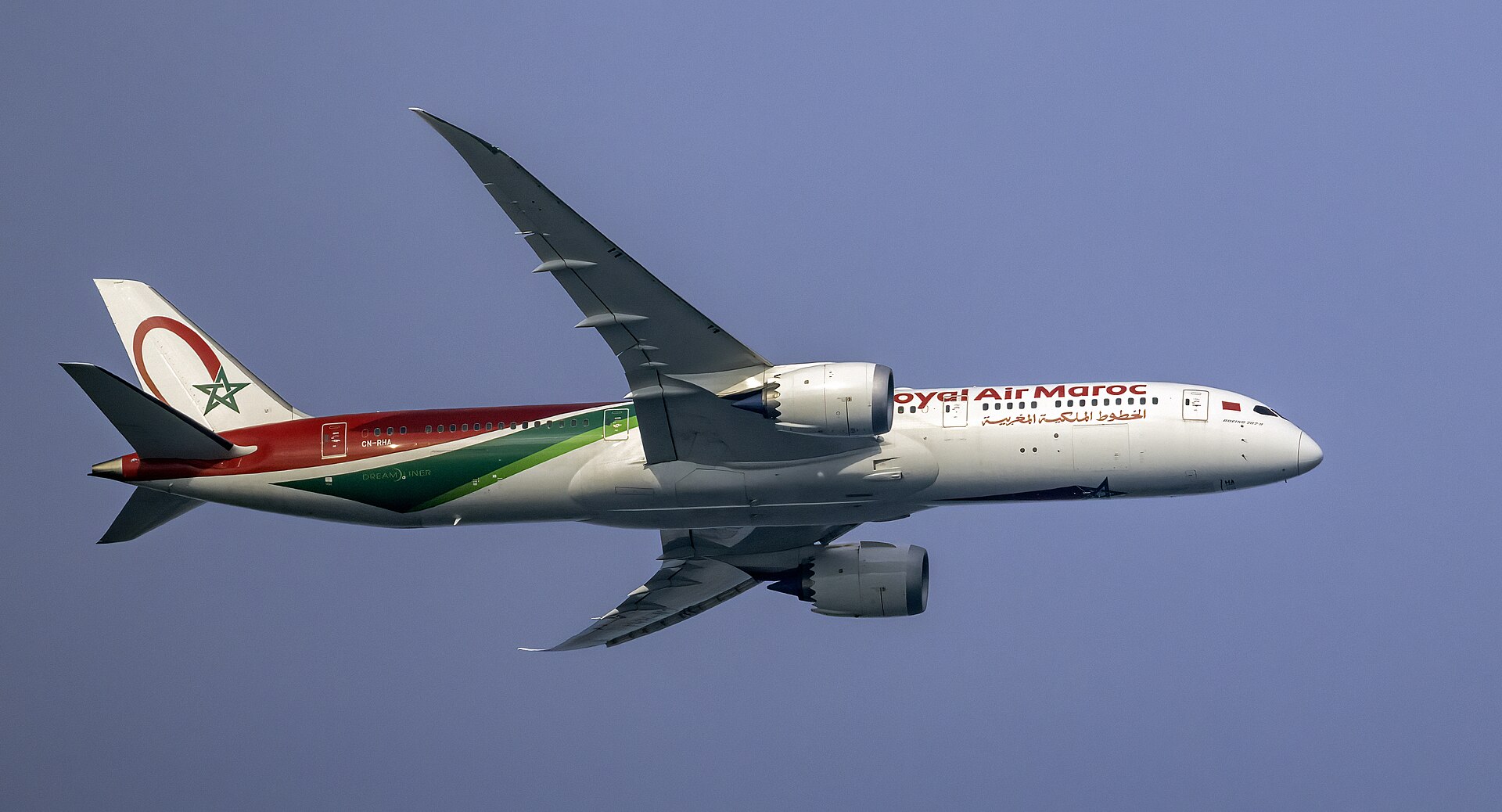 A Royal Air Maroc Boeing 787-9 Dreamliner in red, green and white livery flying against a blue sky