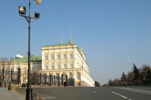 The Grand Kremlin Palace in Moscow, a yellow and white building with a green roof, seen from the street on a clear autumn day