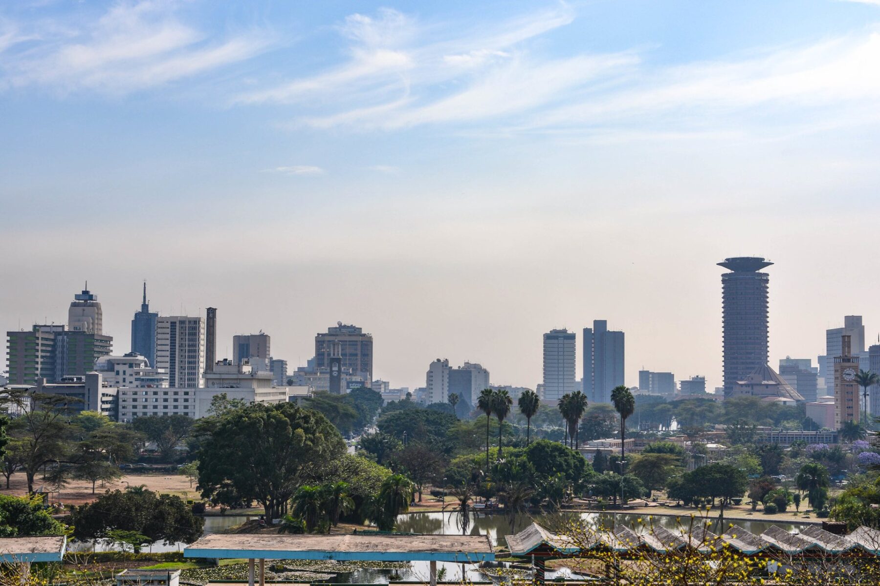 Nairobi skyline seen from Uhuru Park, with palm trees, a lake and the Kenyatta International Convention Centre tower on the right