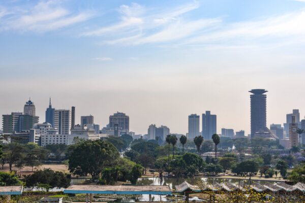 Nairobi skyline seen from Uhuru Park, with palm trees, a lake and the Kenyatta International Convention Centre tower on the right