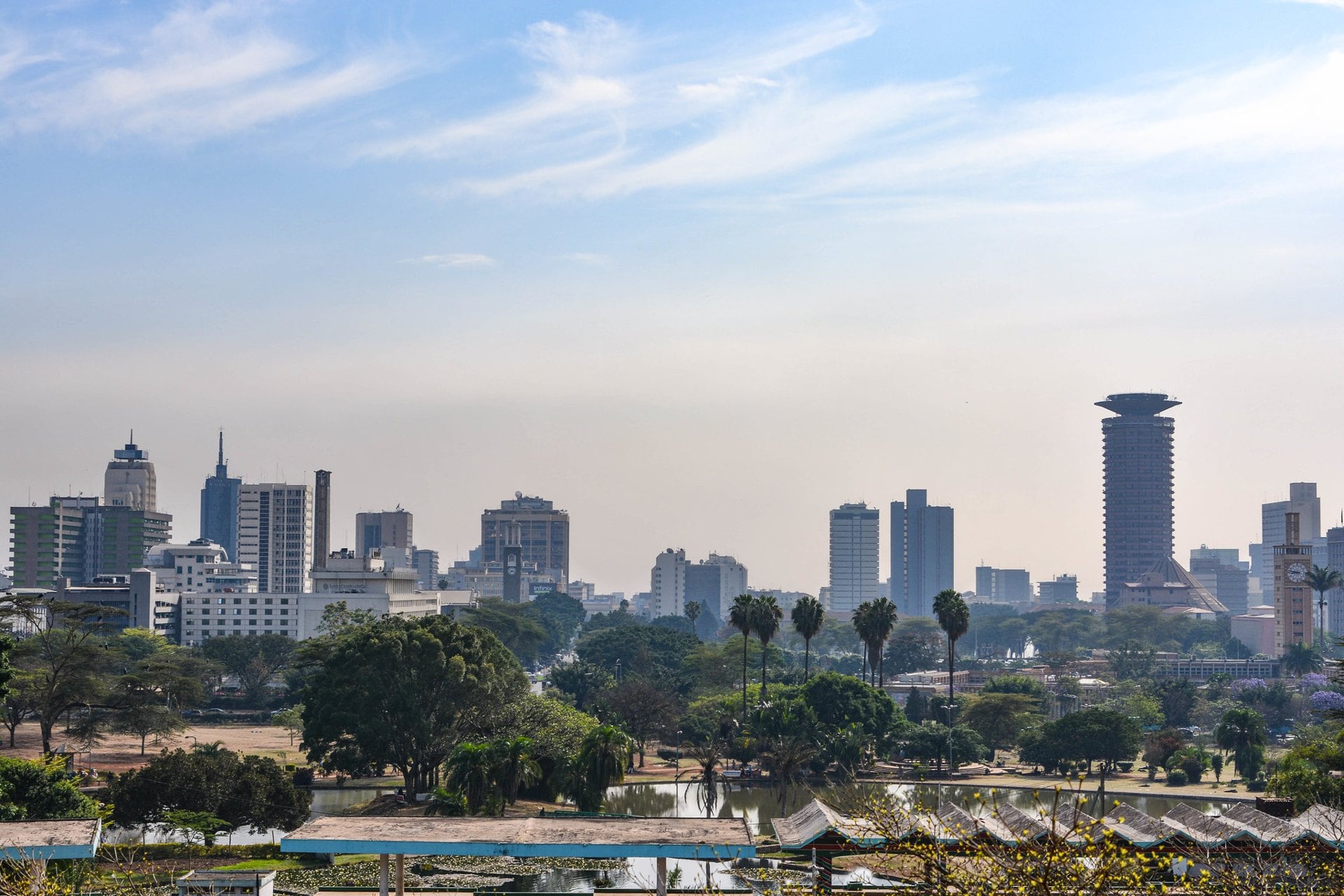 Nairobi skyline seen from Uhuru Park, with palm trees, a lake and the Kenyatta International Convention Centre tower on the right