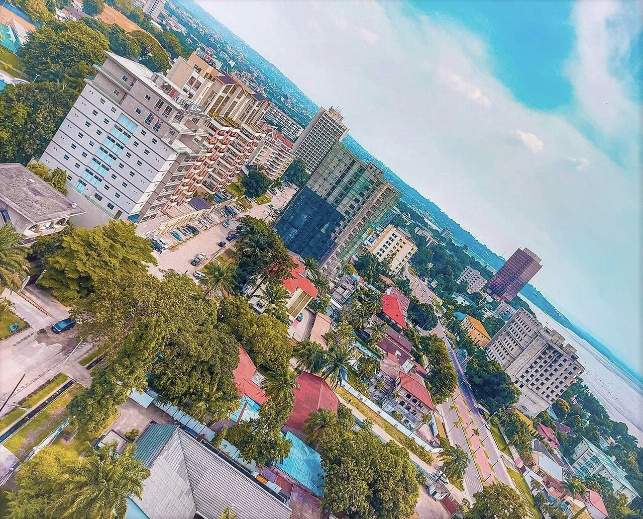 Aerial view of office towers, apartment blocks and palm trees in Kinshasa, with the Congo River on the horizon