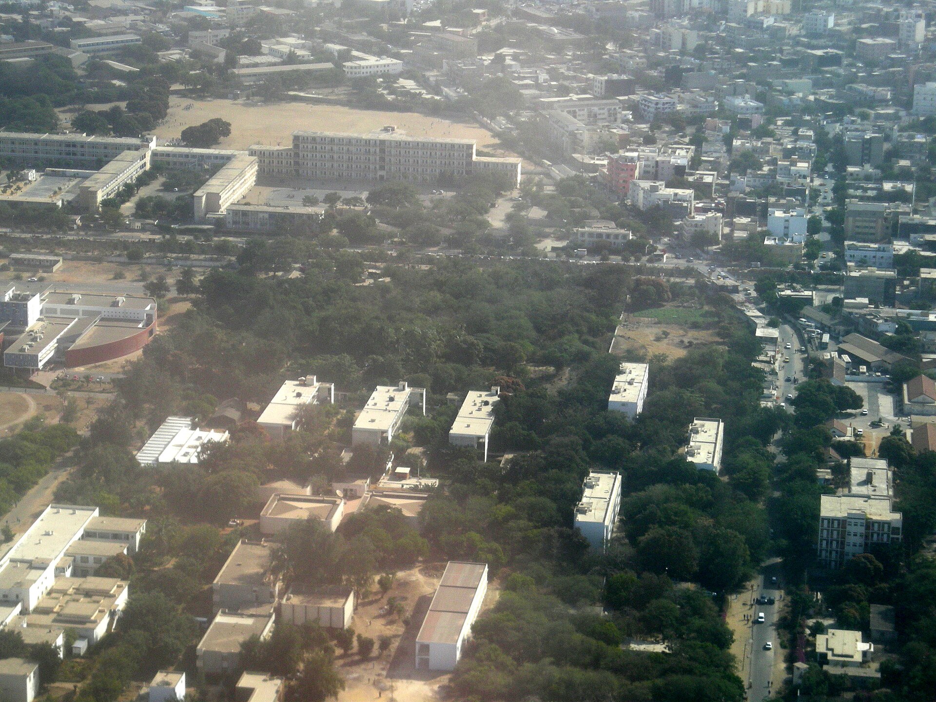 Aerial view of Dakar with low-rise buildings among trees in the foreground and denser neighbourhoods in the background