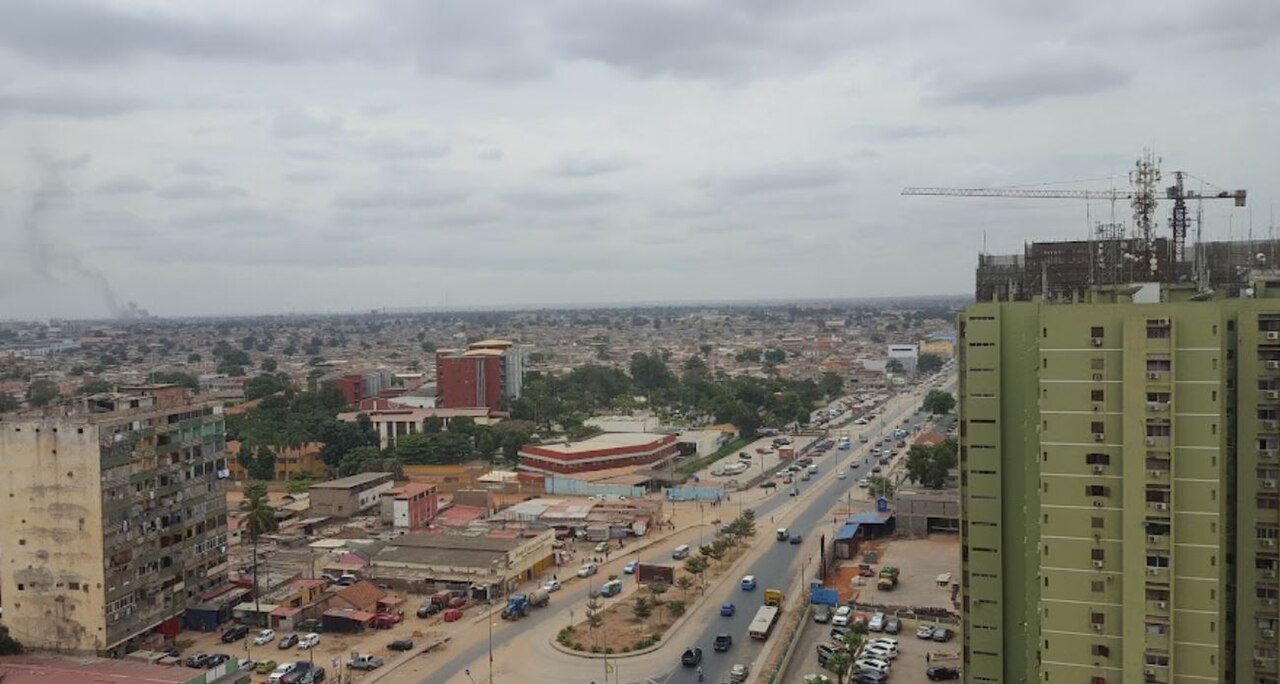 A busy road through the Rangel district of Luanda with apartment blocks and a construction crane