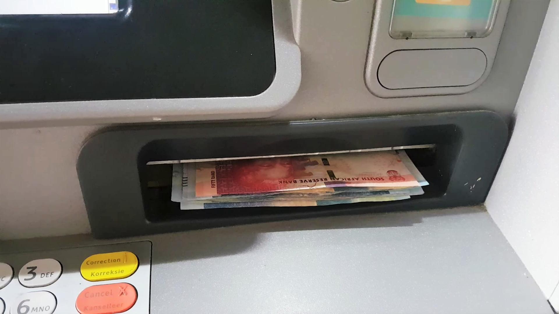 Banknotes in the cash slot of an ATM in South Africa, with part of the keypad visible