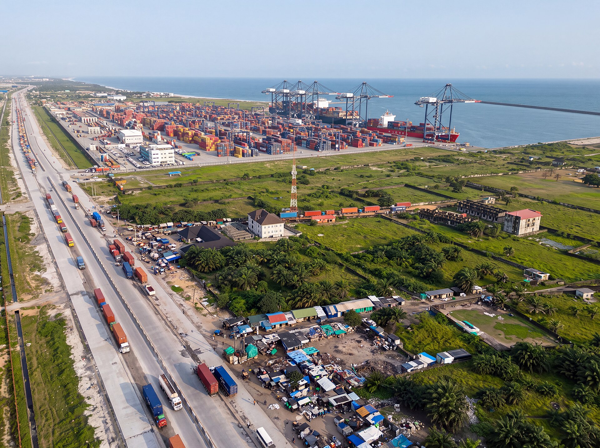 Aerial view of the Lekki Deep Sea Port east of Lagos with ship-to-shore cranes, a container ship at the quay, stacked containers and queuing trucks