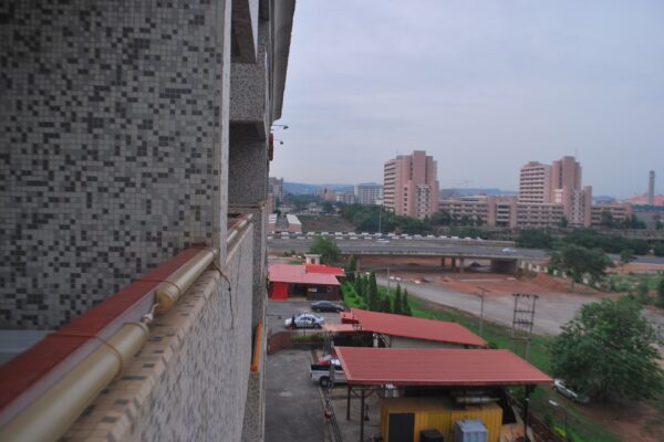 View from a tiled building over central Abuja, Nigeria, with high-rise blocks, red-roofed sheds and an elevated road