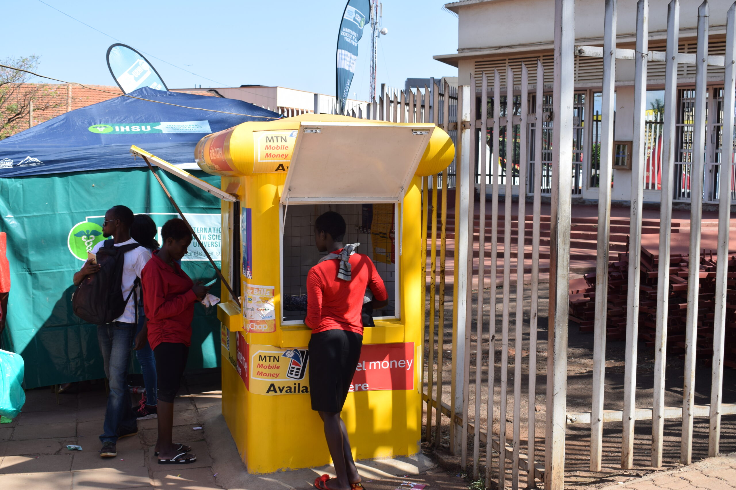 Customers at a yellow mobile money kiosk on an African street