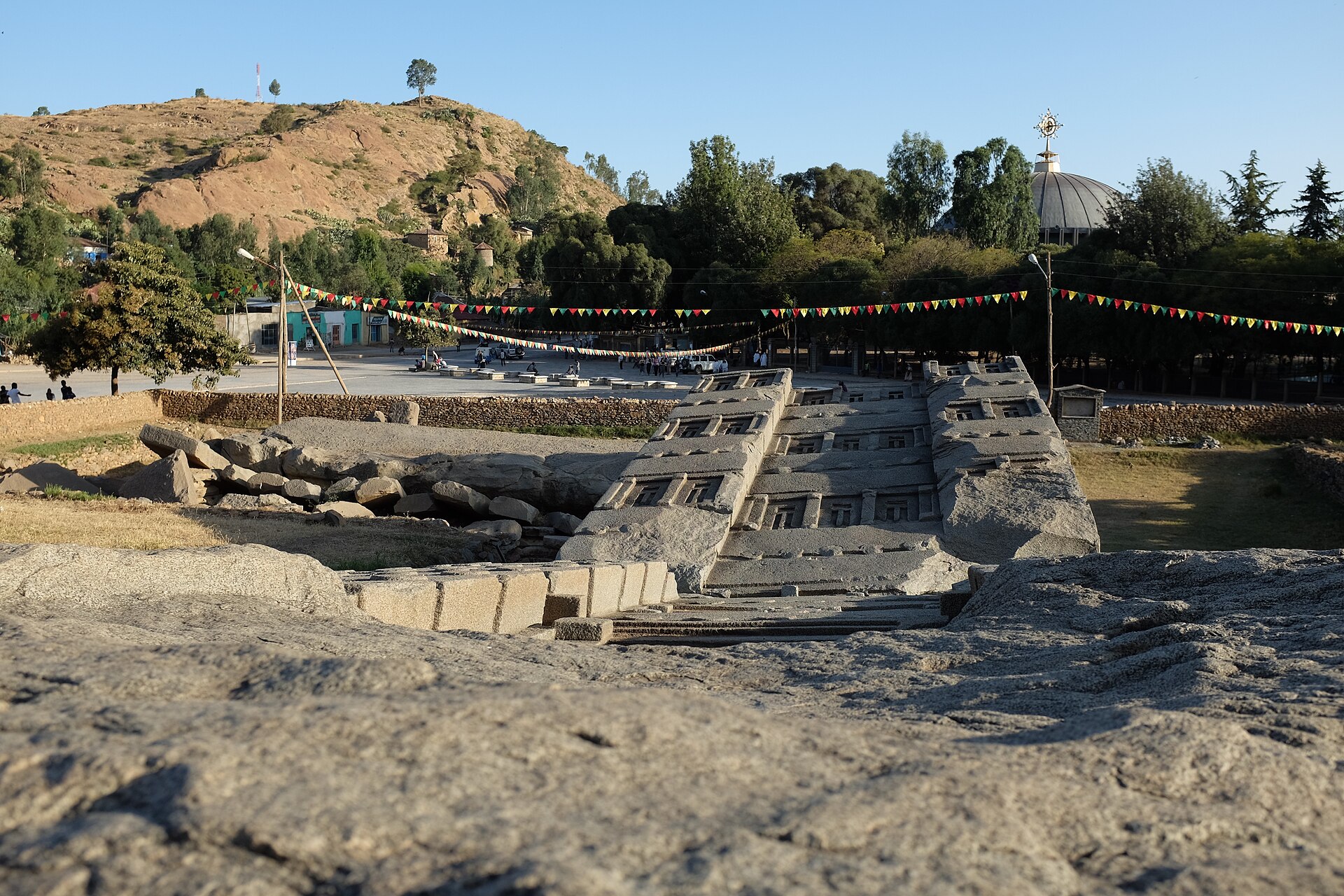 The fallen Great Stele in the stelae field of Aksum, Tigray, with a church dome behind