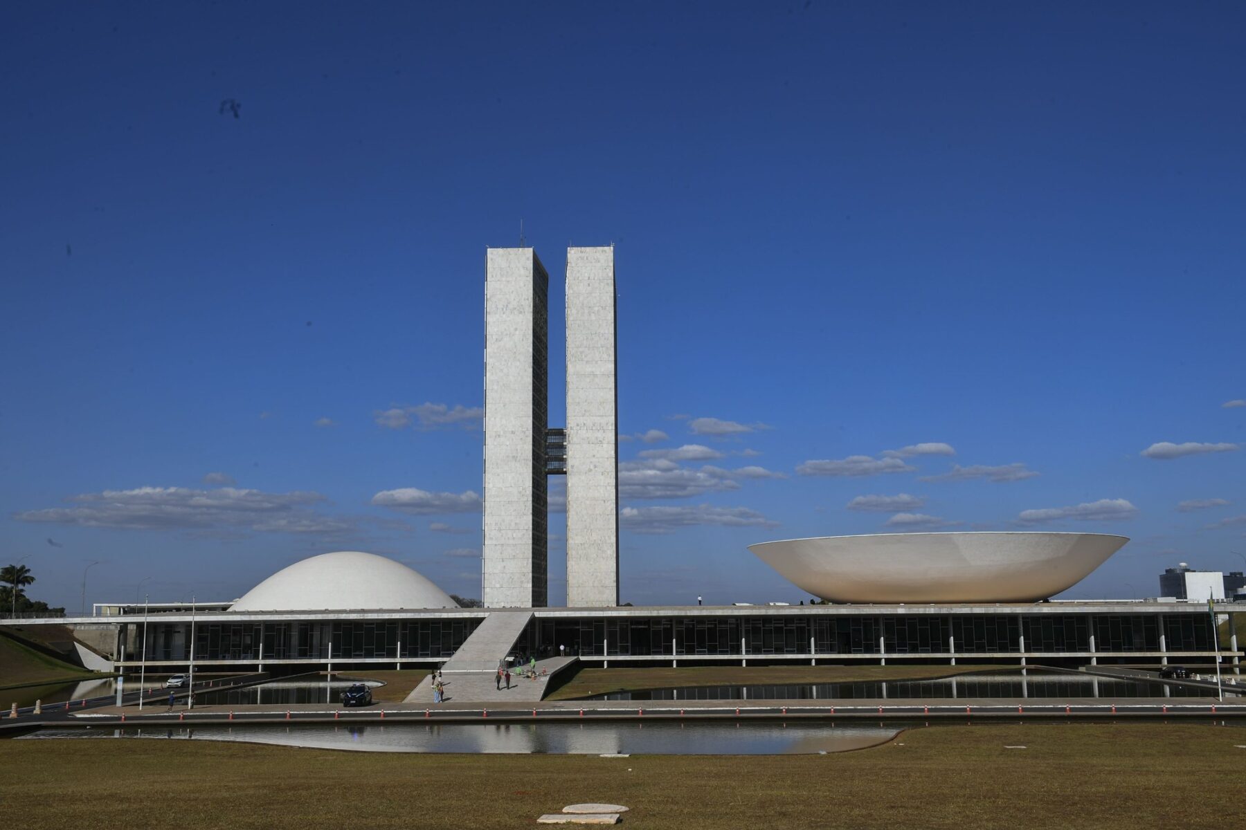 The twin office towers and the two domes of the National Congress building in Brasília under a blue sky