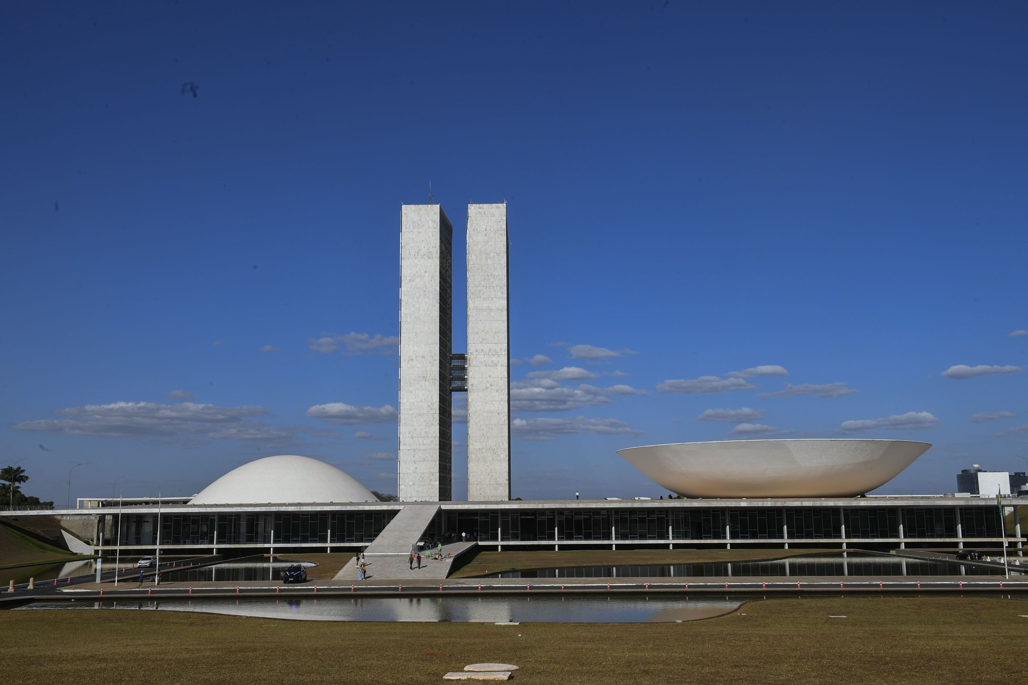 The twin office towers and the two domes of the National Congress building in Brasília under a blue sky