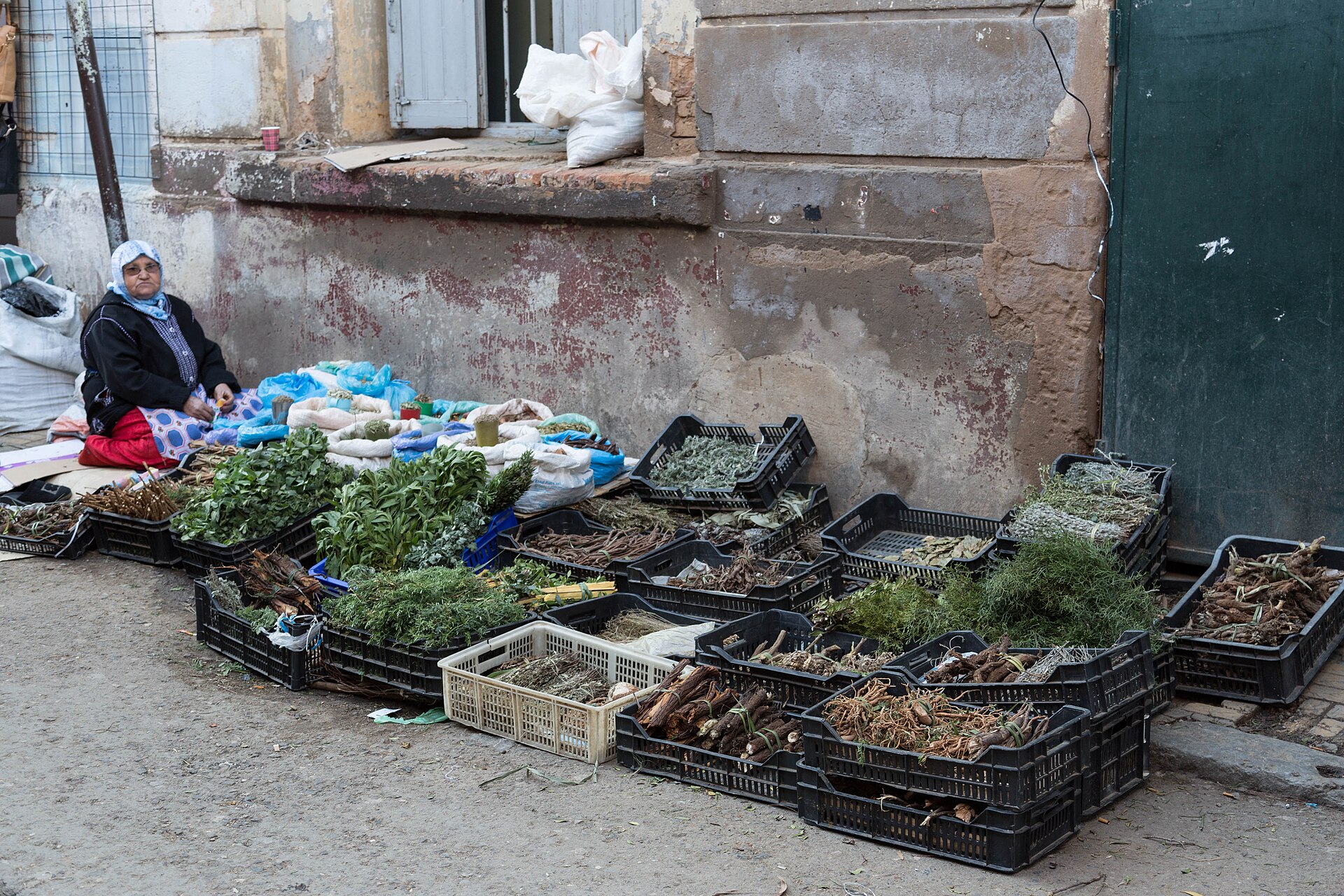 A herb and spice seller with crates of dried and fresh herbs in a street market in Tlemcen, Algeria