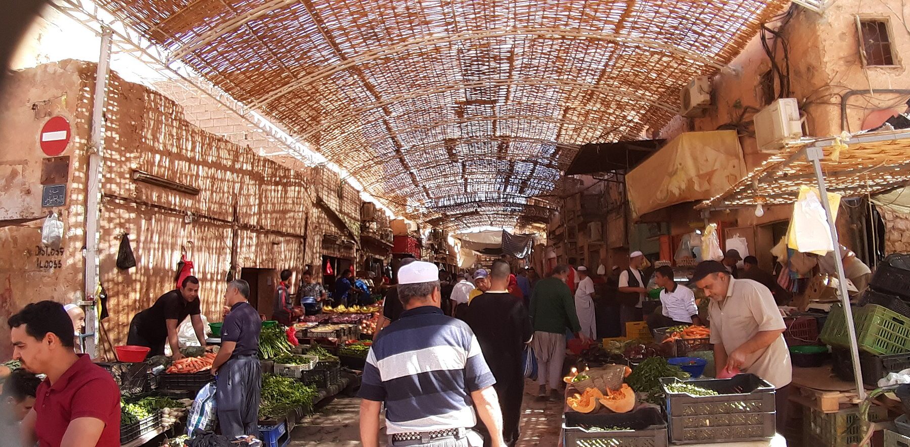 Shoppers and vegetable sellers under a reed-covered street in the market of Ghardaia, Algeria