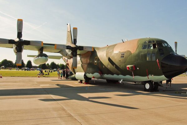 An Algerian Air Force Lockheed C-130H Hercules transport with olive and tan camouflage parked on an apron at an air show