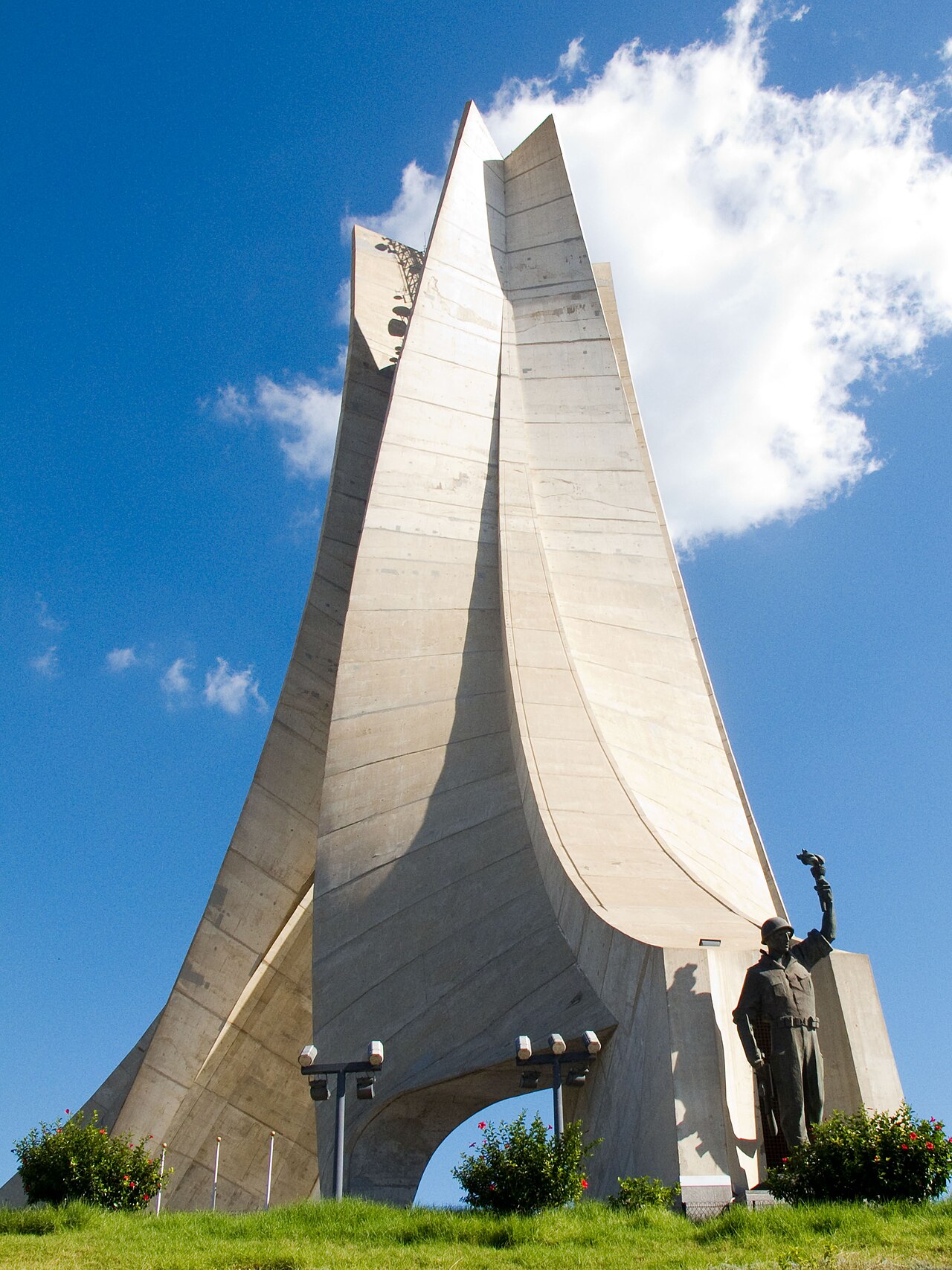 The Martyrs' Memorial in Algiers, three tall concrete fronds rising above a hill, with a bronze soldier at its foot