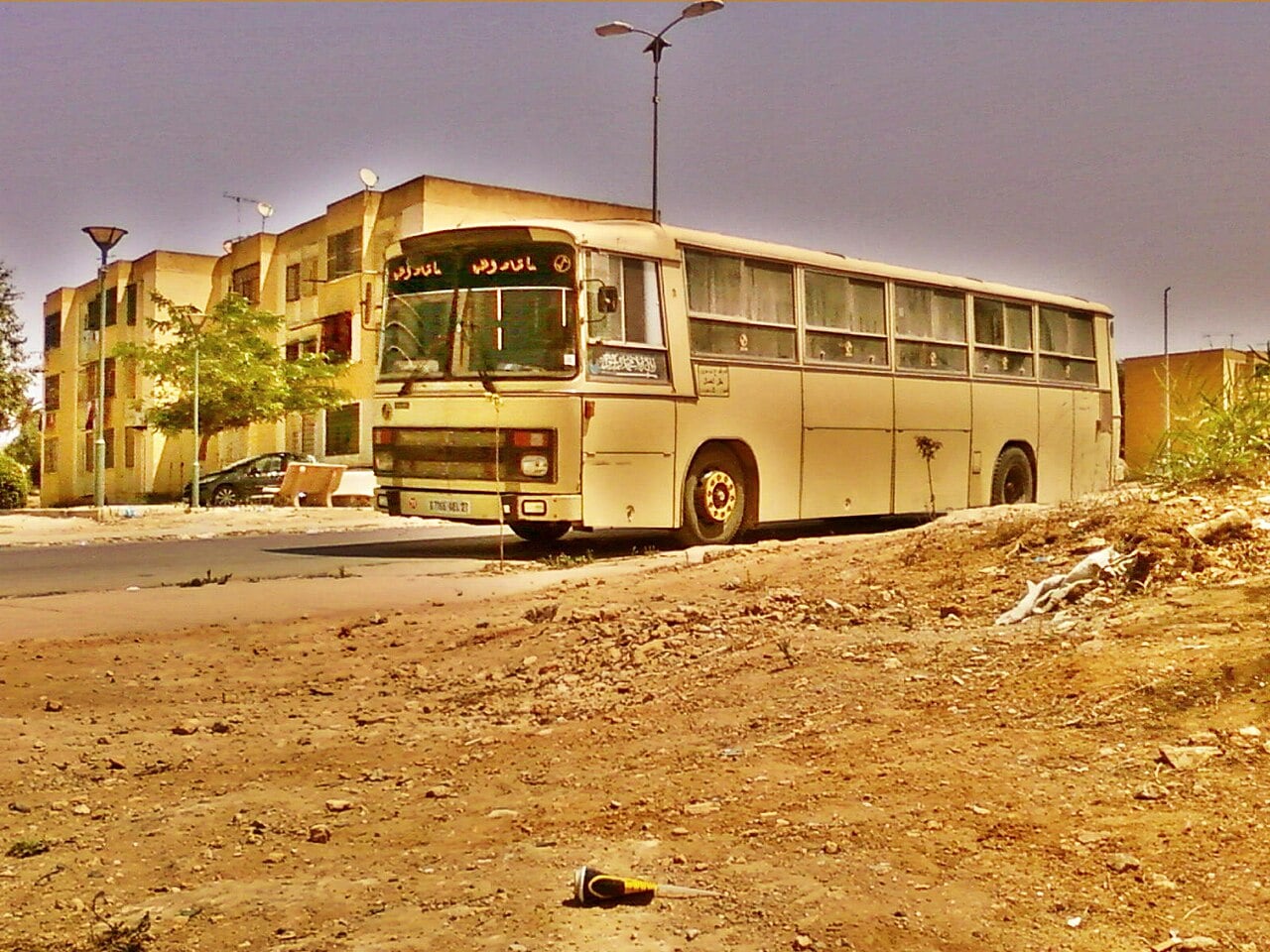 A cream-coloured SNVI bus parked beside apartment blocks in Oran, Algeria