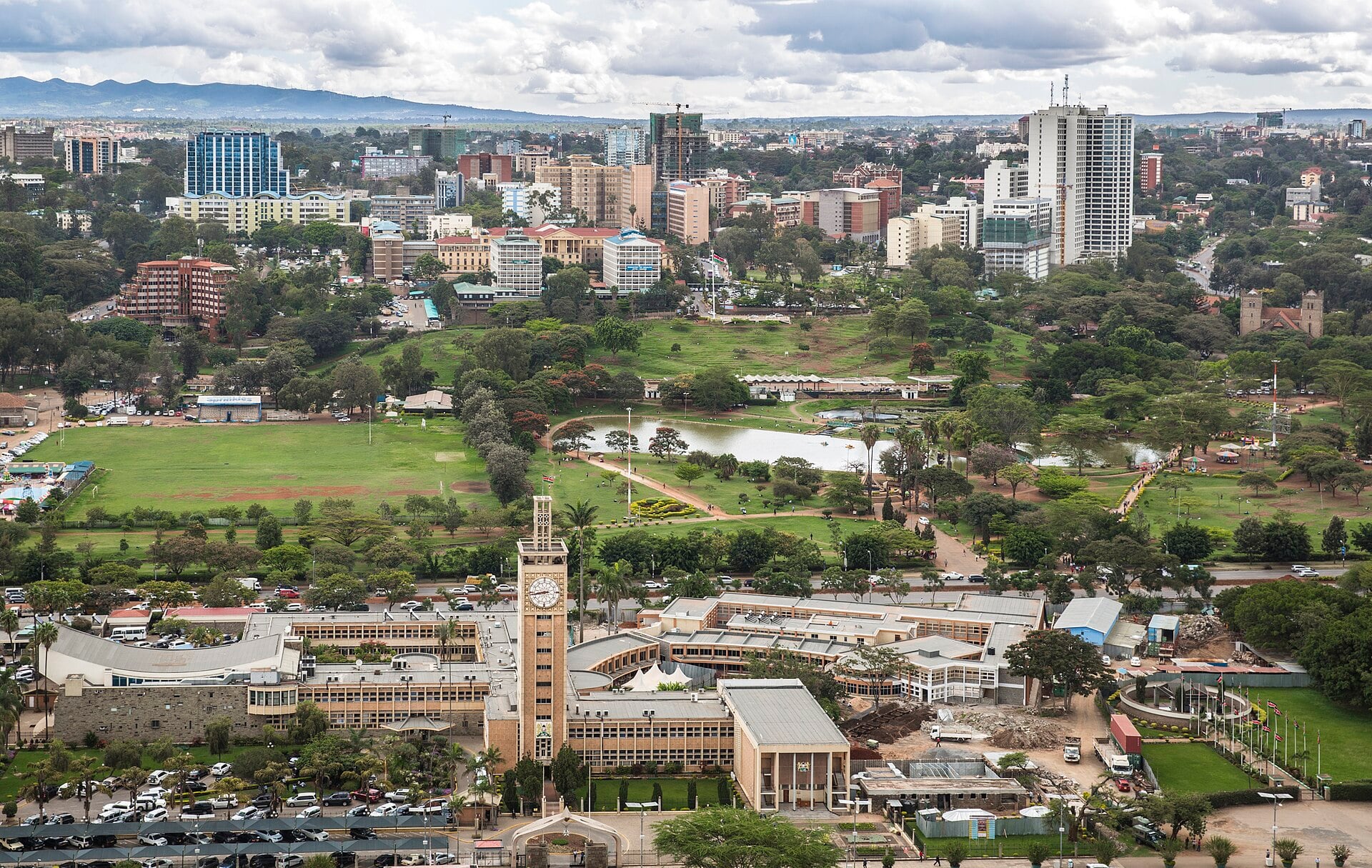 Elevated view of Kenya's Parliament Buildings with their clock tower, Uhuru Park's lake and lawns, and the Nairobi skyline behind