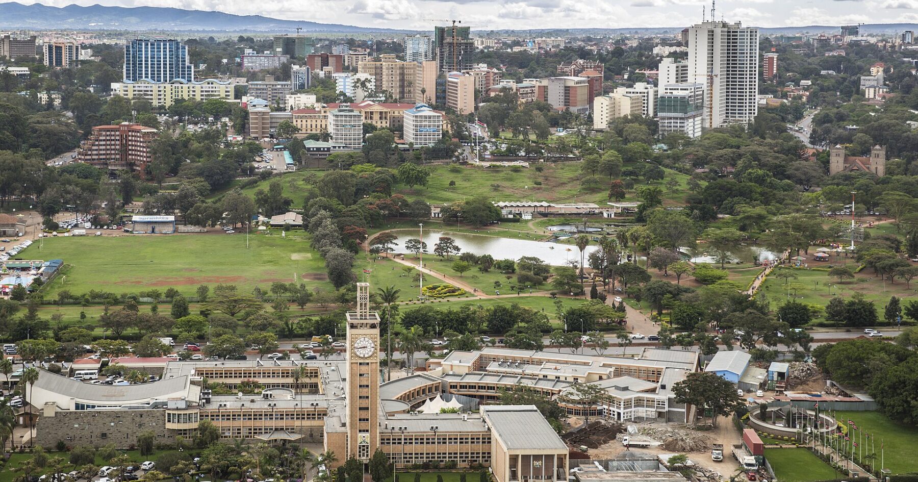 Elevated view of Kenya's Parliament Buildings with their clock tower, Uhuru Park's lake and lawns, and the Nairobi skyline behind