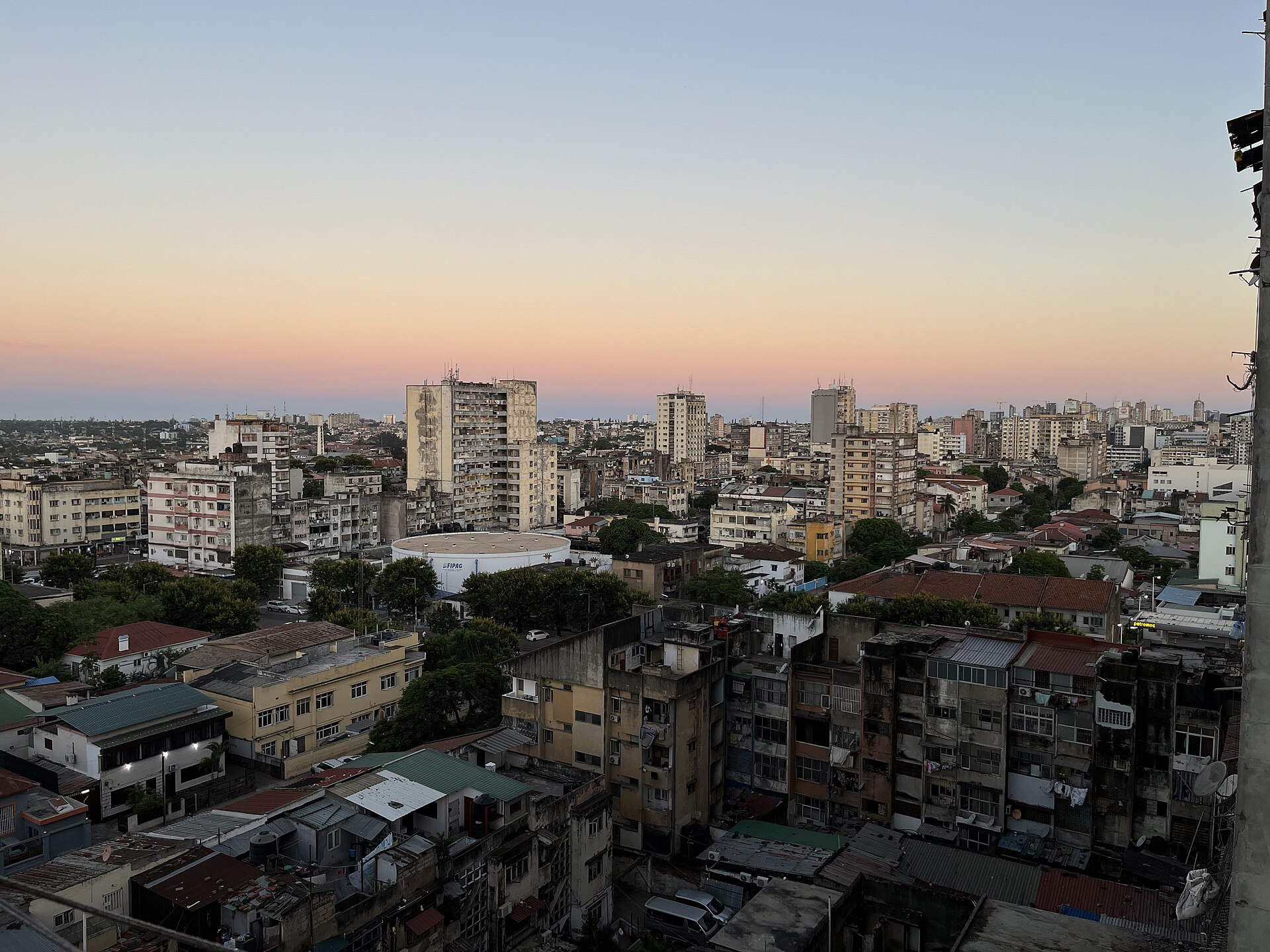Apartment blocks and rooftops in central Maputo under an orange and blue dusk sky