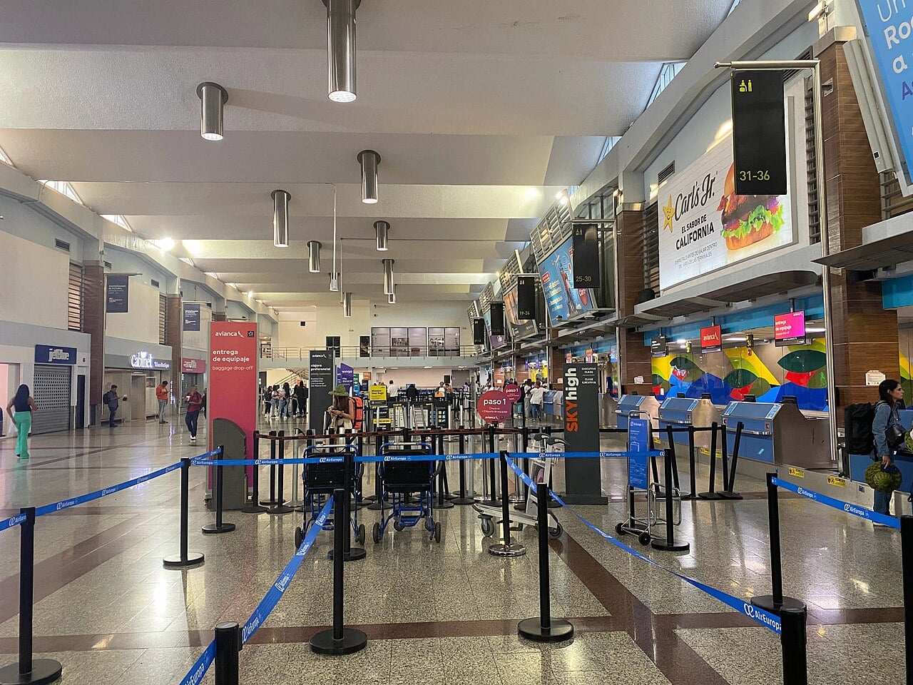 The check-in hall at Las Américas International Airport in Santo Domingo, with queue barriers, airline counters and travellers with luggage