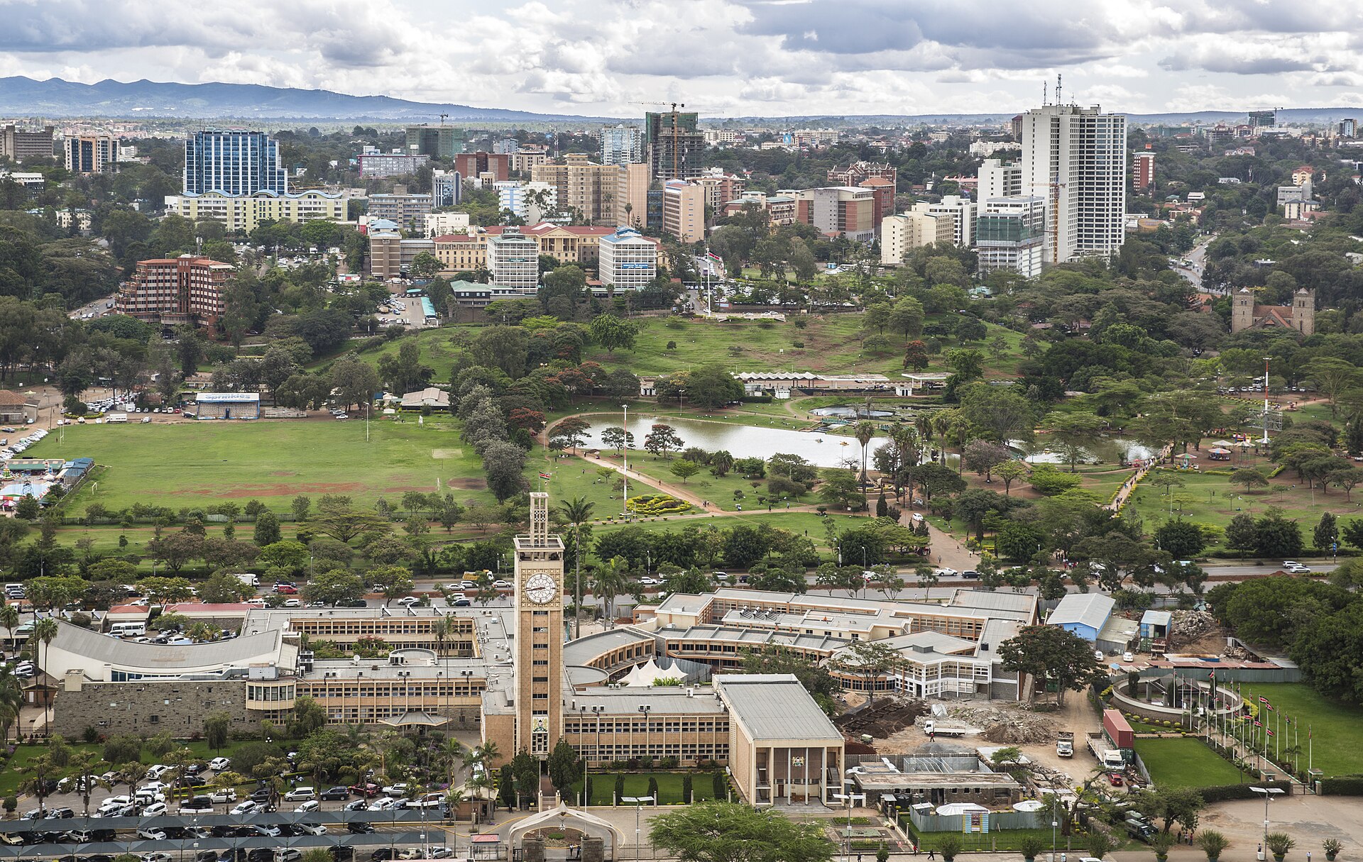 Elevated view of Kenya's Parliament Buildings with their clock tower, Uhuru Park's lake and lawns, and the Nairobi skyline behind