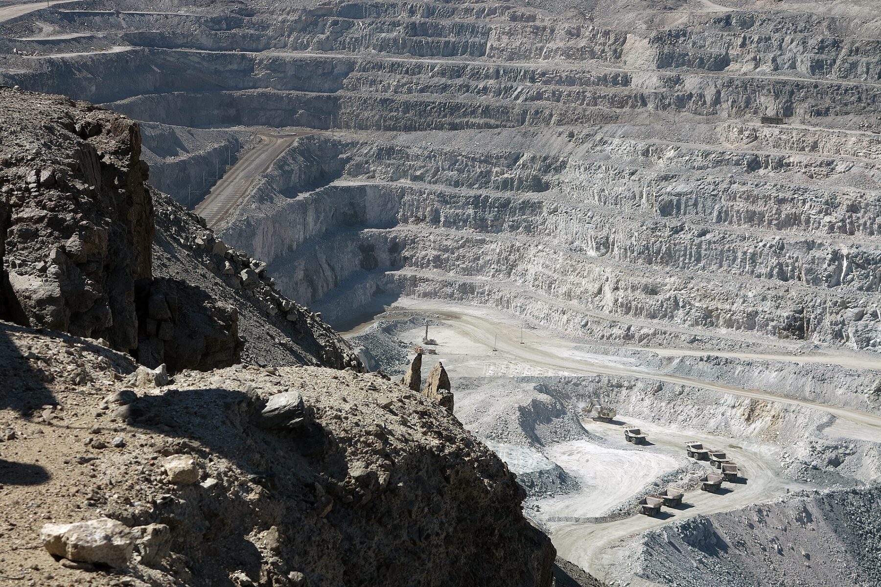 Terraced open pit of the Rossing uranium mine in Namibia's Erongo region with haul trucks on the pit floor