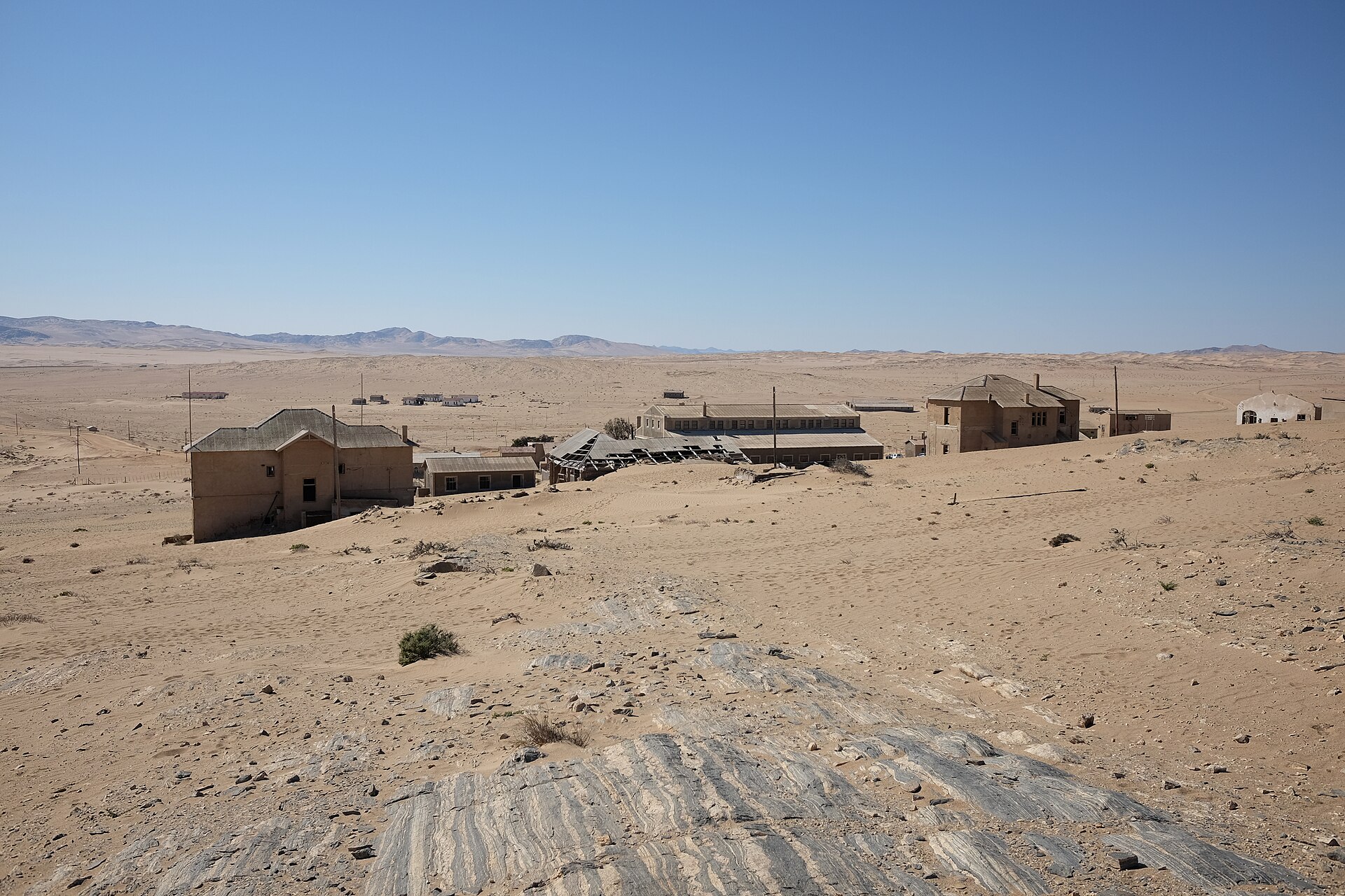 Sand-filled abandoned buildings of Kolmanskop in the Namib desert under a clear blue sky