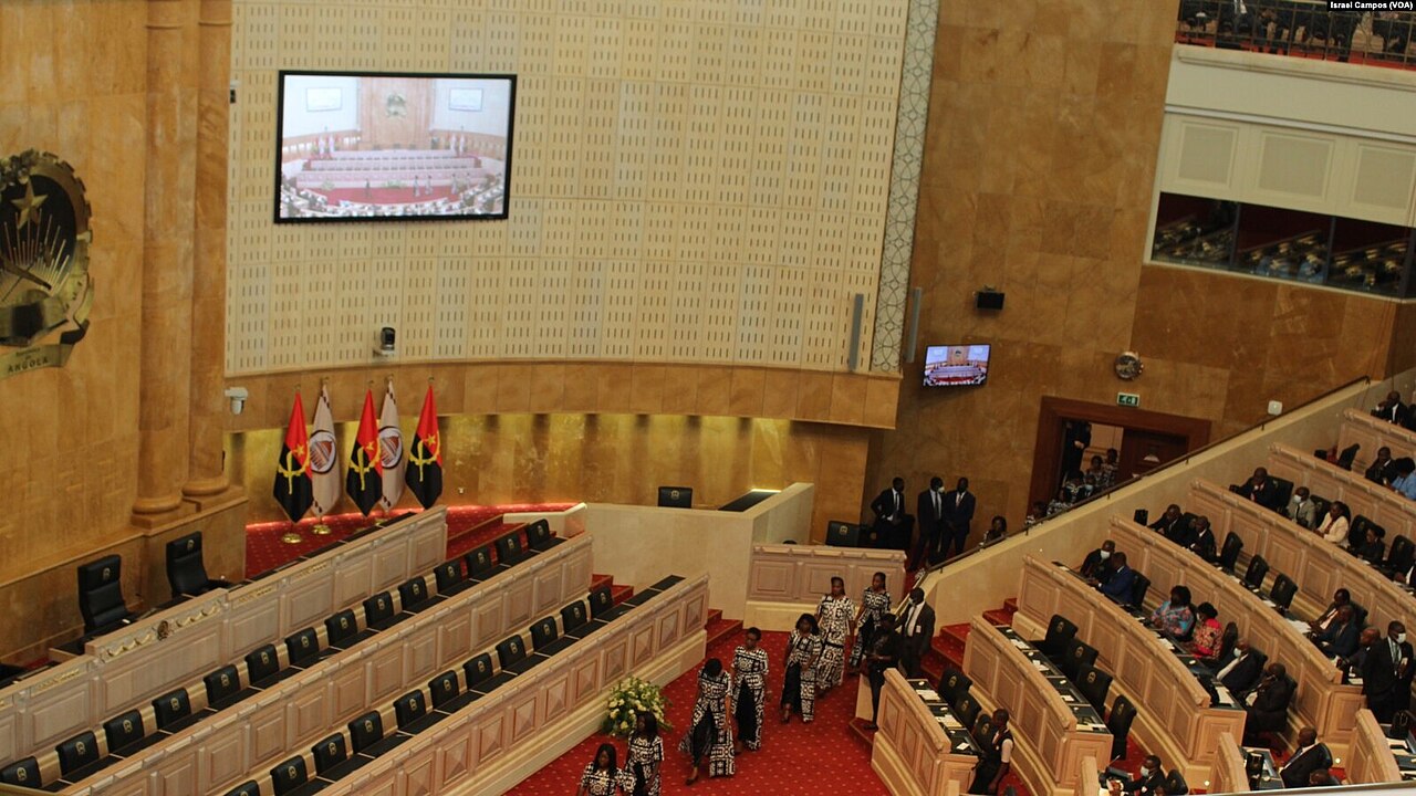 Delegates in the red-carpeted chamber of Angola's National Assembly in Luanda, with national flags and a wall screen