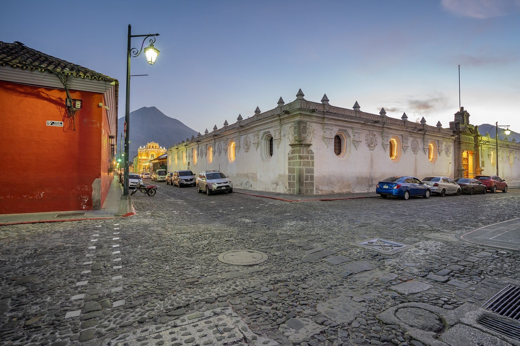 Cobbled street in Antigua Guatemala at dusk with a volcano behind