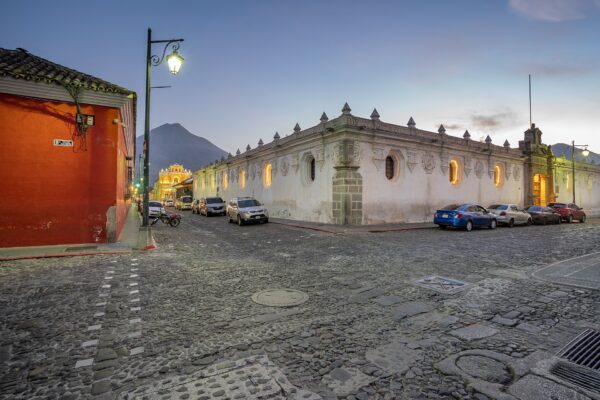 Cobbled street in Antigua Guatemala at dusk with a volcano behind