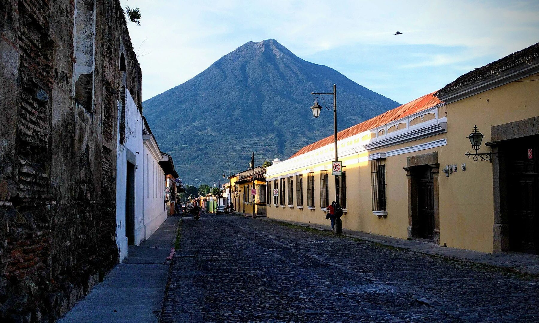 Antigua Guatemala in October: a cobbled colonial street with yellow houses leading to the cone of Volcán de Agua