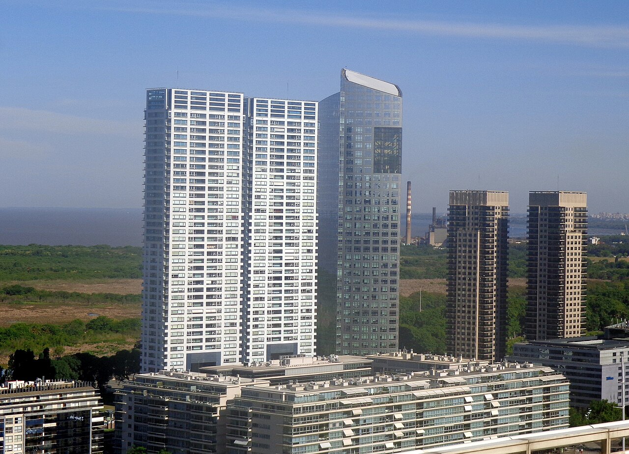 The glass Torre YPF headquarters rising beside white residential towers in Puerto Madero, Buenos Aires, with the River Plate behind.