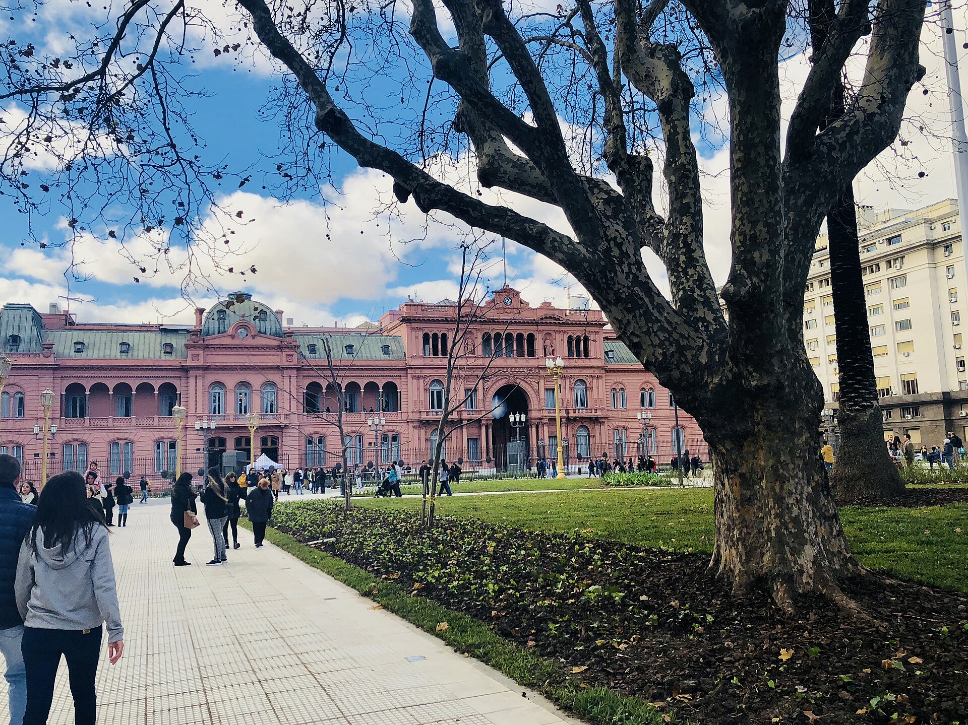 Pedestrians walk toward the pink Casa Rosada presidential palace on Plaza de Mayo, Buenos Aires, Argentina