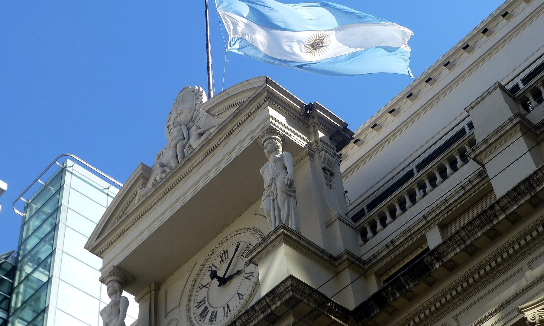 Argentine flag flying above the clock and facade of the central bank headquarters in Buenos Aires