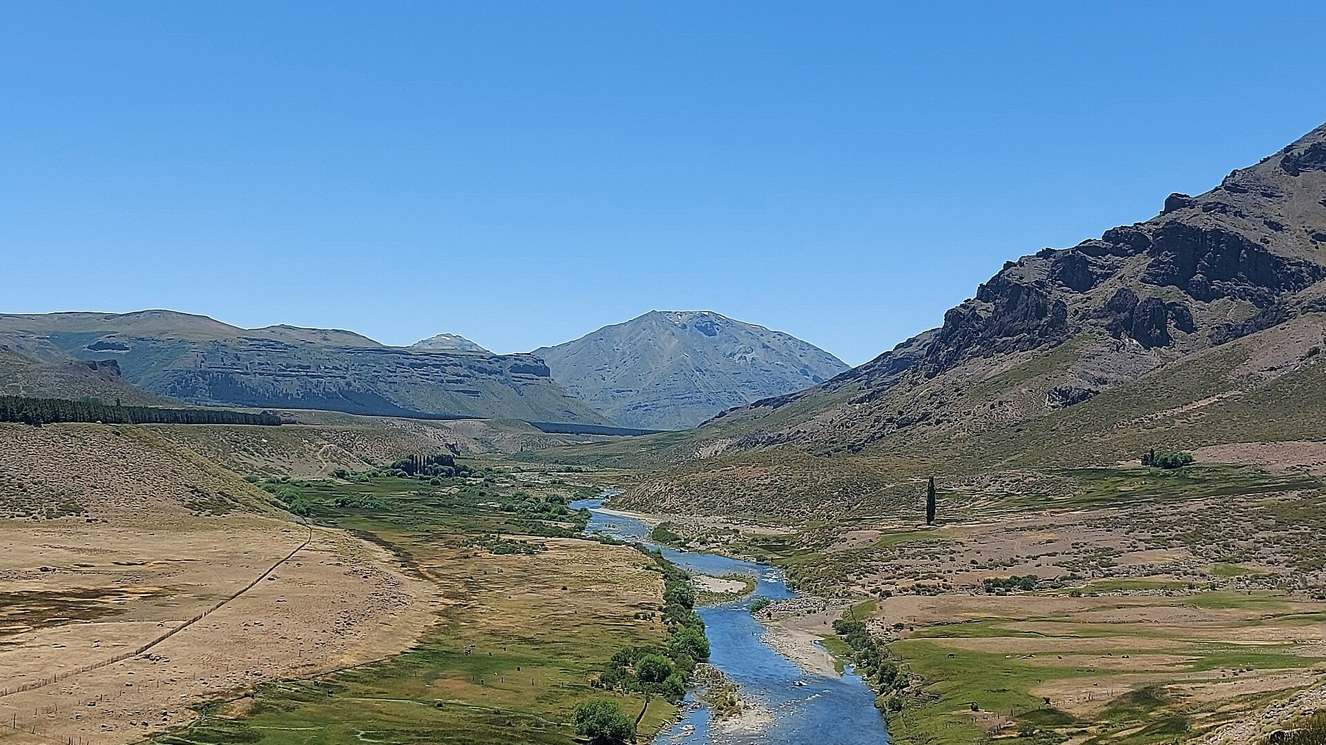 The Neuquén River winding through a mountain valley in northern Neuquén province, Argentina, under a clear sky