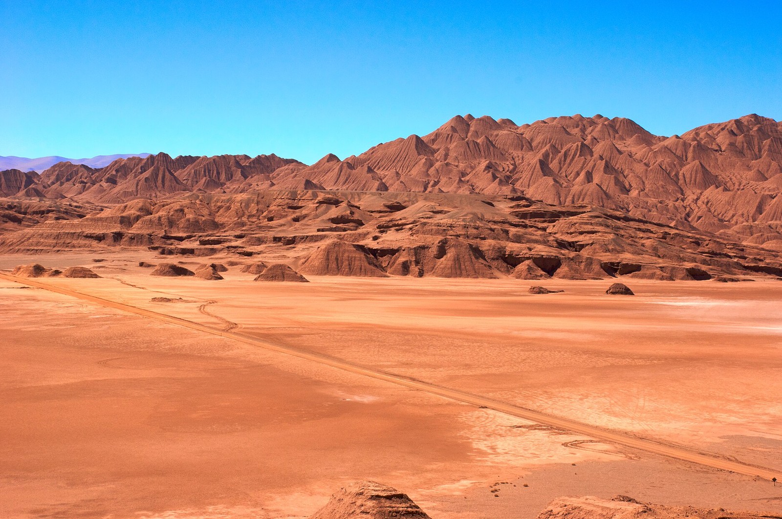 Eroded red hills and a dirt road across the desert near Tolar Grande, Salta province, Argentina