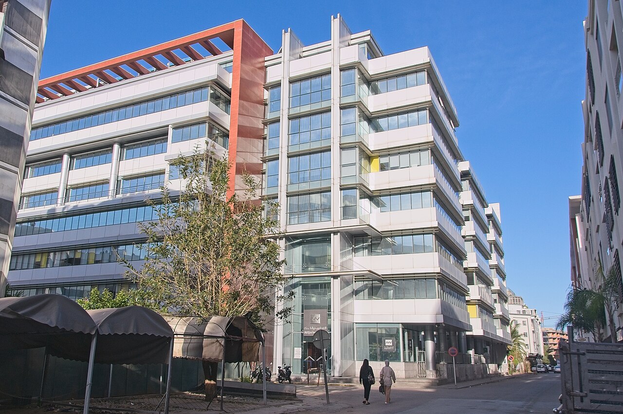Glass and white office building of Attijariwafa bank on a Casablanca street under a blue sky