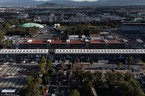 Main grandstand of the Autódromo Hermanos Rodríguez with Mexico City and mountains behind it.