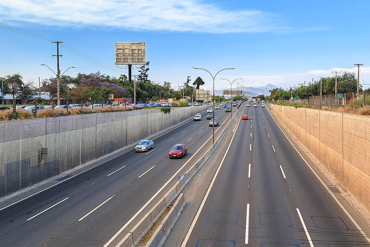 Cars driving on the sunken lanes of Autopista Central near El Parrón in southern Santiago, with the Andes behind