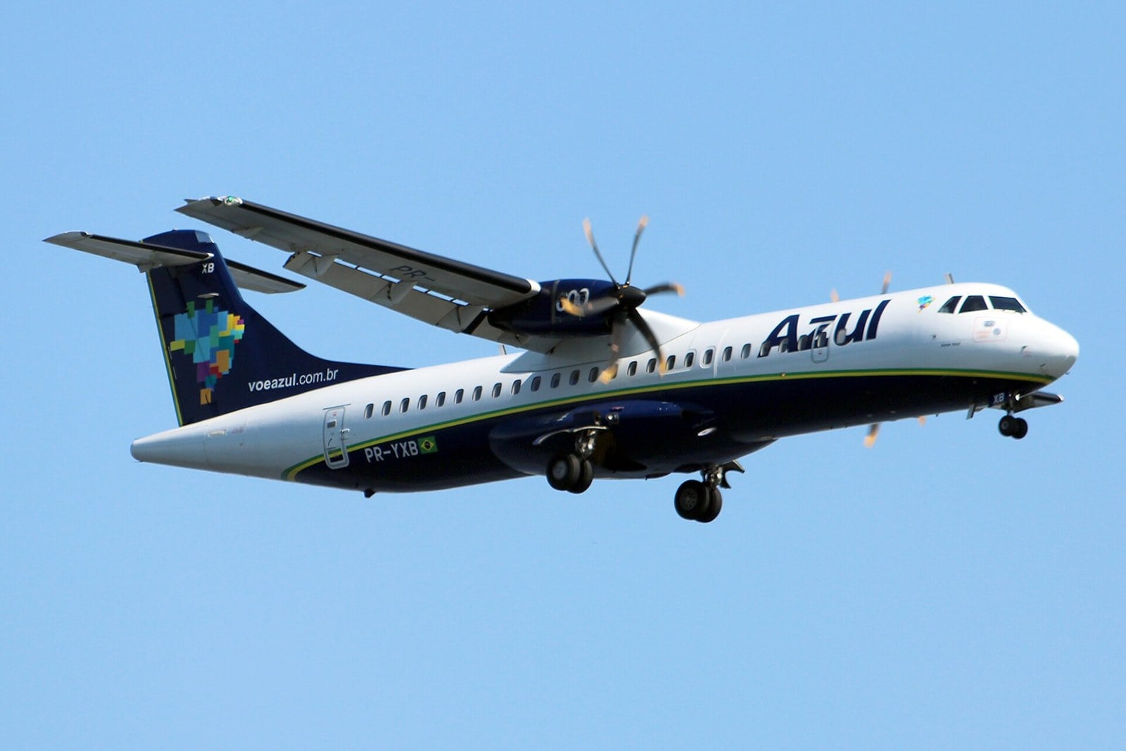 Azul ATR 72 turboprop with its landing gear down, seen from below against a clear blue sky
