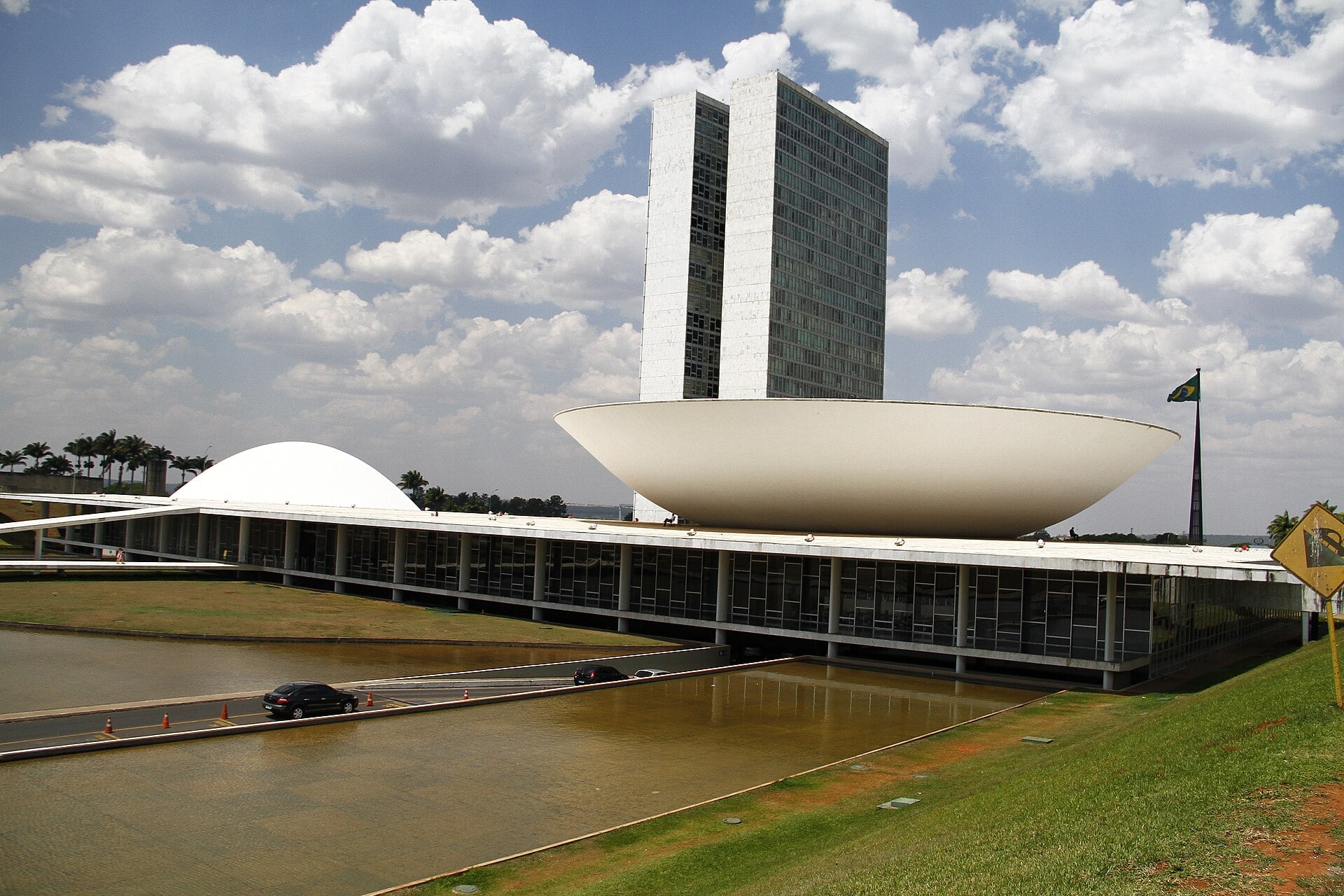 The National Congress in Brasilia with its twin office towers and white bowl-shaped Senate dome under a cloudy sky