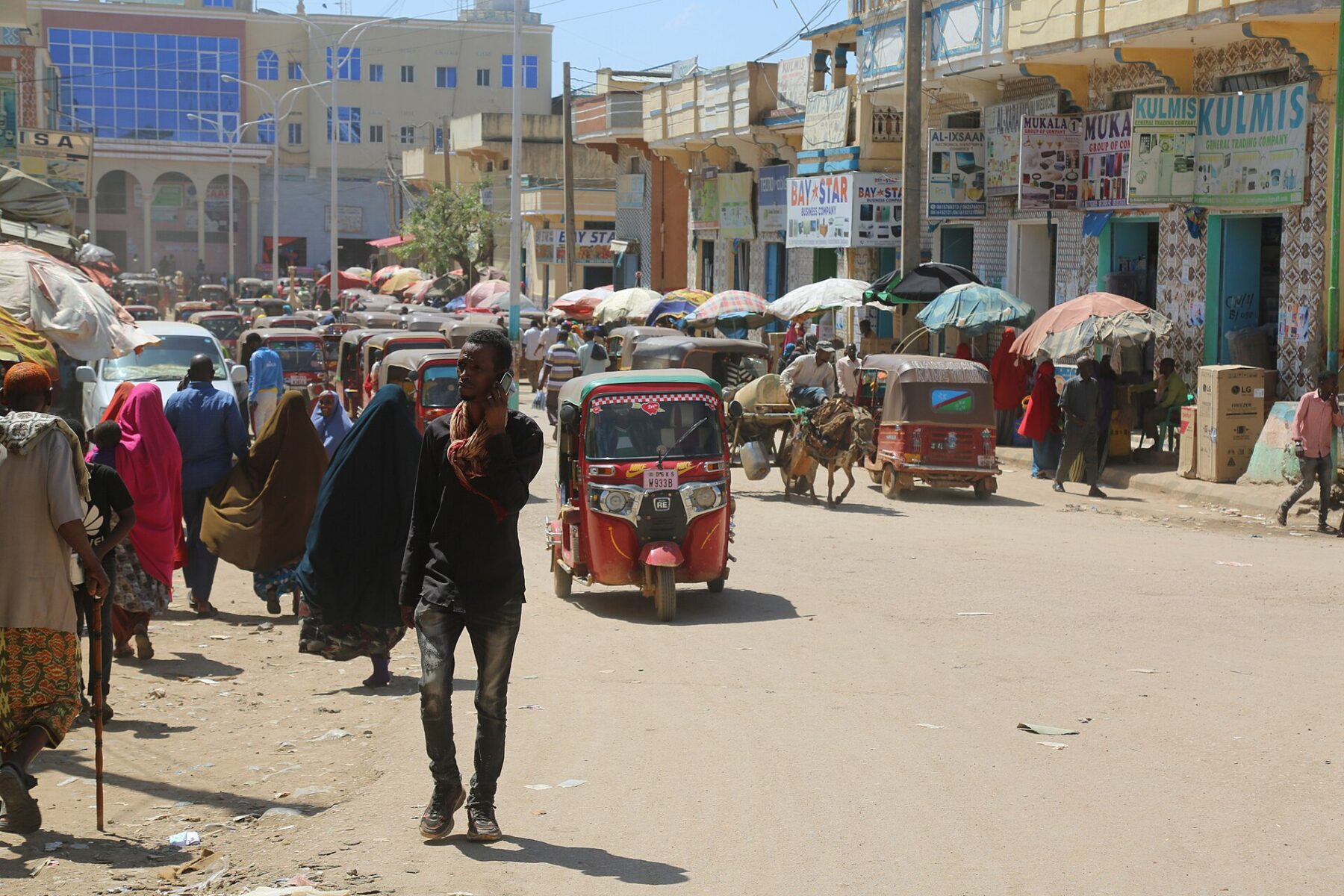 A busy market street with tuk-tuks and pedestrians in Baidoa, Somalia